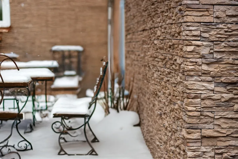 Weatherproof decorative stone wall with snow-covered patio in winter