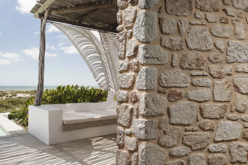Mediterranean terrace with natural stone wall cladding in sandy tones and sea view.